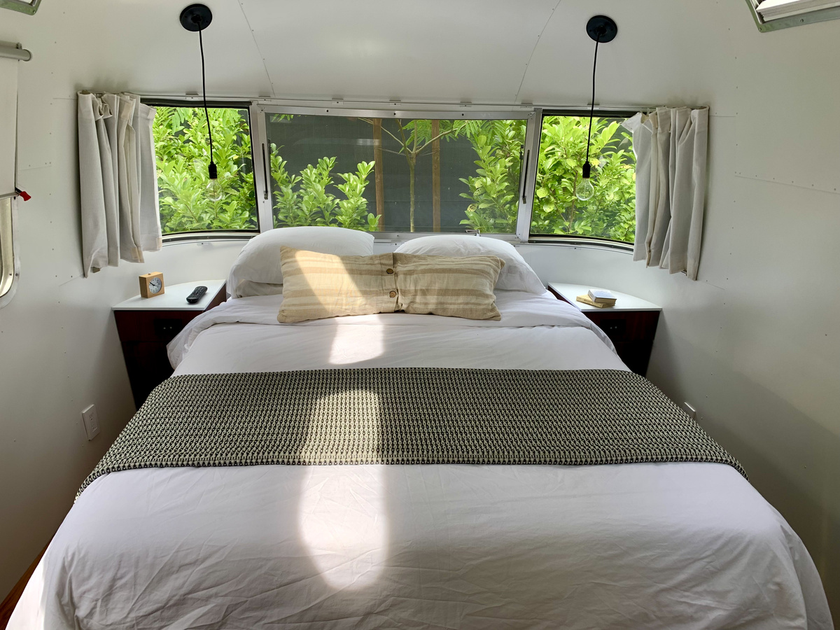 Double bed beneath panoramic windows in an Airstream trailer