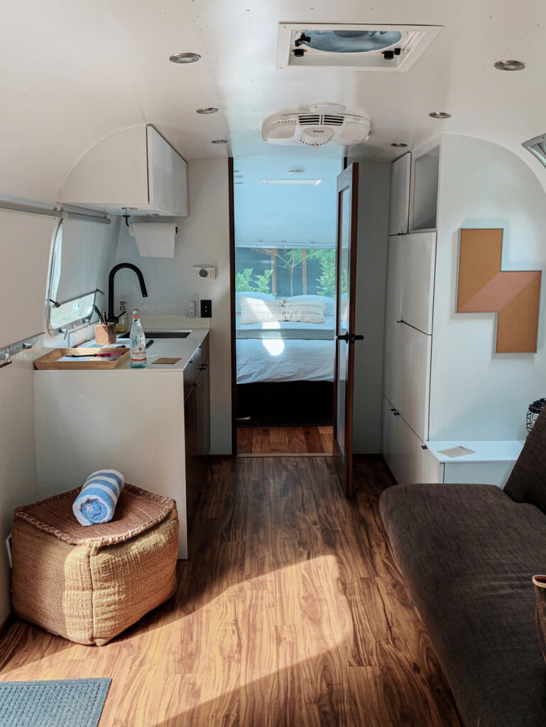 Compact Airstream interior with kitchenette, sofa and the bedroom visible beyond