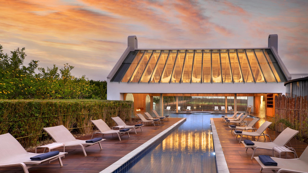 The Garden Spa pool at Babylonstoren, with loungers on wooden decks and a glass-roofed pavilion at sunset.