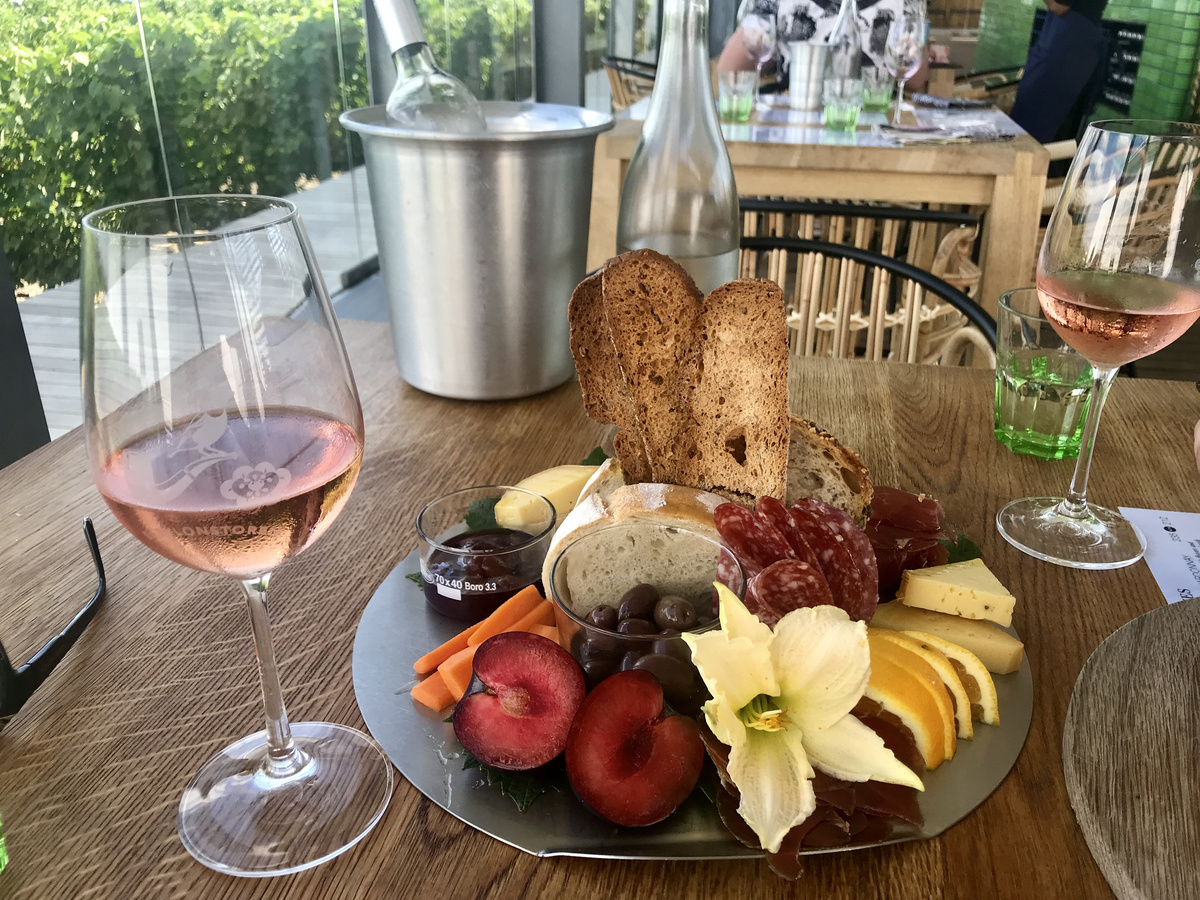 Rosé, fruit, cheese, charcuterie and bread on a table overlooking vines at Babylonstoren.