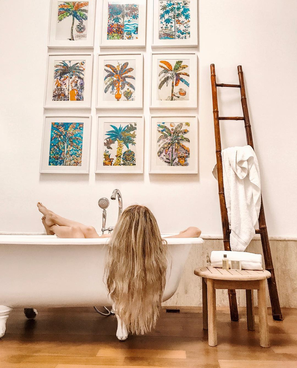 Olga relaxes in a freestanding bath beneath nine colourful palm artworks at Casas del XVI in 2018.