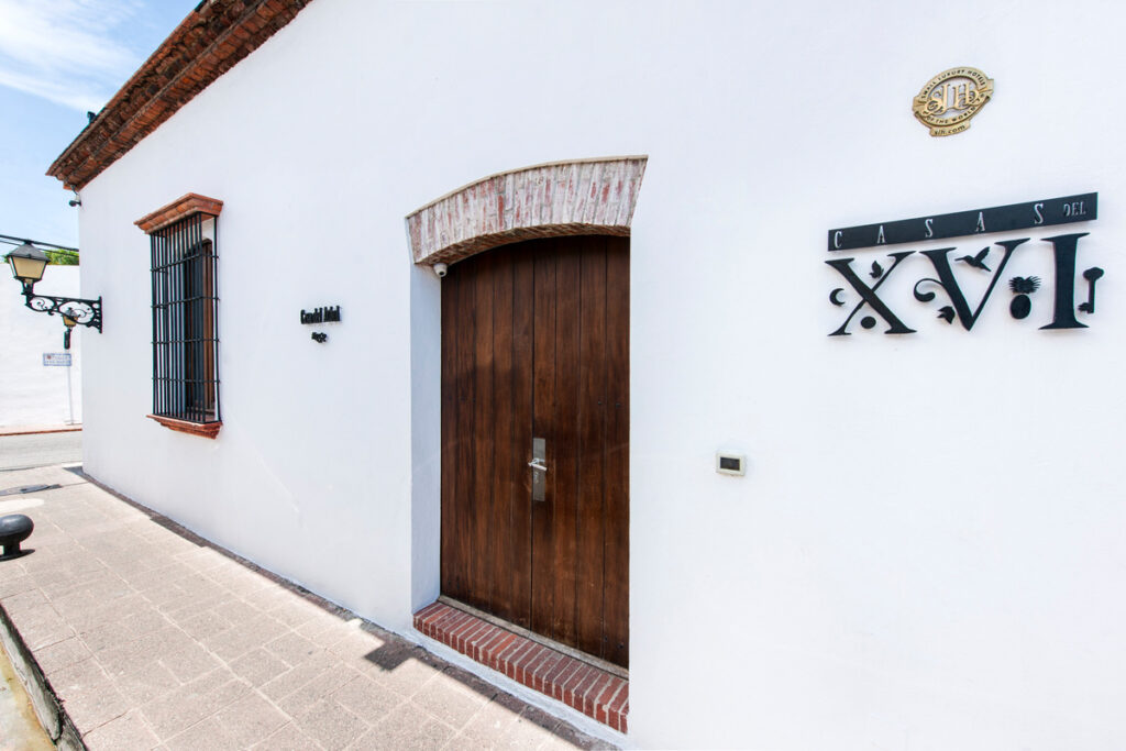 A whitewashed Casas del XVI house with a wooden door opens directly onto a street in Santo Domingo’s Colonial City.