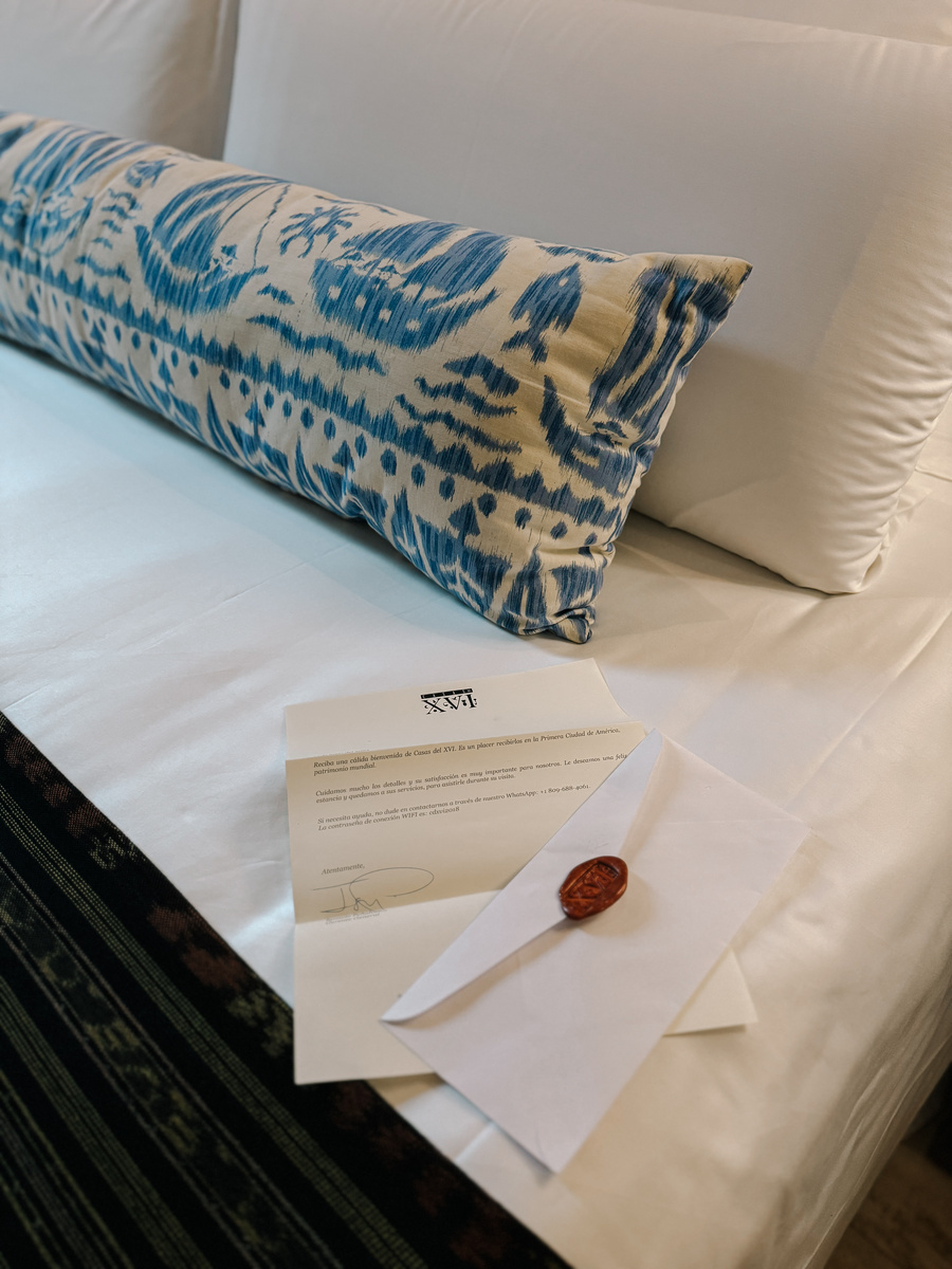 A handwritten welcome letter and wax-sealed envelope rest on a blue-and-white cushion at Casa del Pozo.