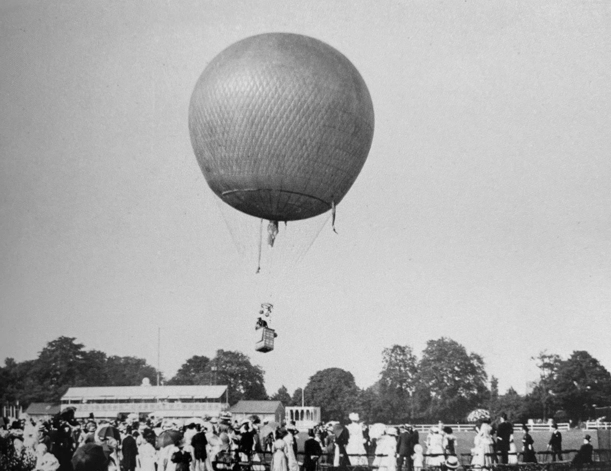 A spherical gas balloon carrying Charles Rolls rises above spectators at the Hurlingham Club in London.