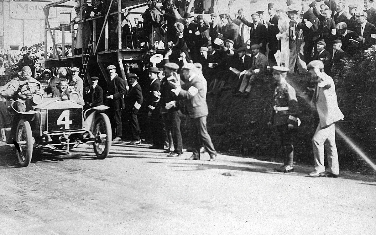 Charles Rolls and Eric Platford in car number four pass a cheering crowd after winning the 1906 Isle of Man Tourist Trophy.