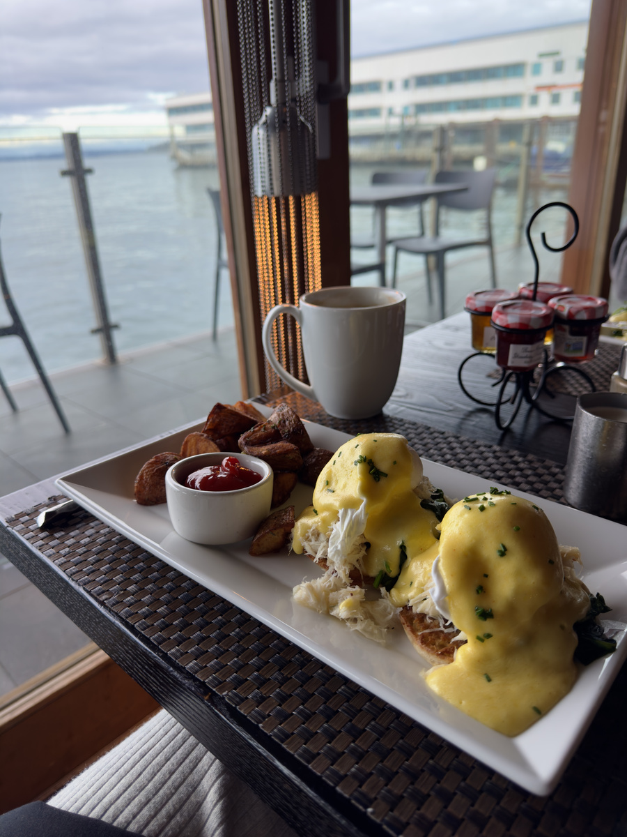 Dungeness crab Benedict with poached eggs, hollandaise and roasted potatoes is served beside an Elliott Bay window at Six Seven Restaurant.