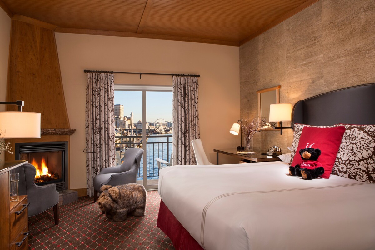 A waterfront guest room at The Edgewater with a fireplace and balcony overlooking Elliott Bay and the Seattle Great Wheel.