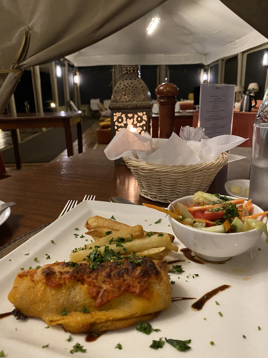 A plated dinner with salad and potatoes in Entim Camp's lantern-lit dining tent.