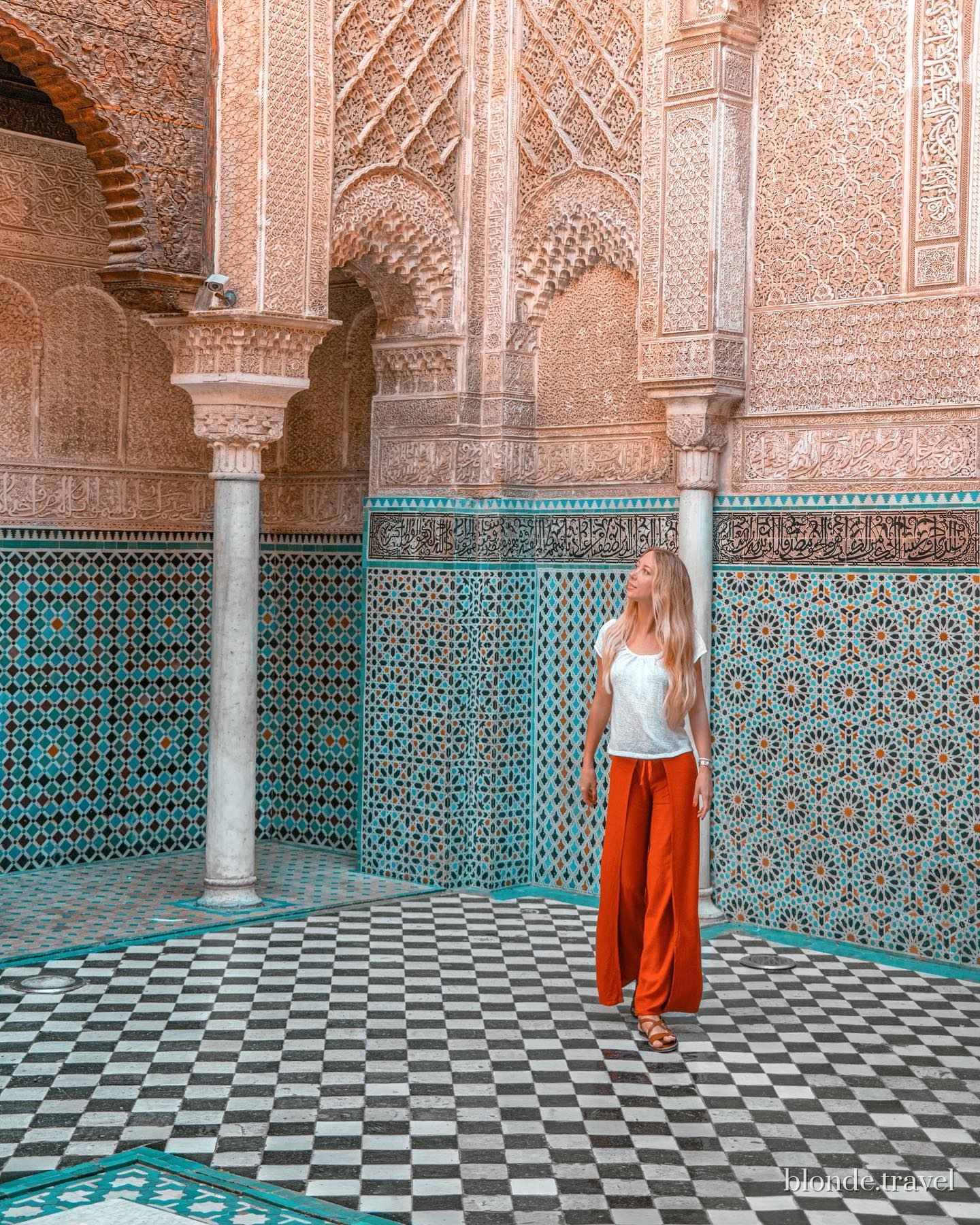 Olga stands beneath carved arches in the tiled courtyard of Al Attarine Madrasa.