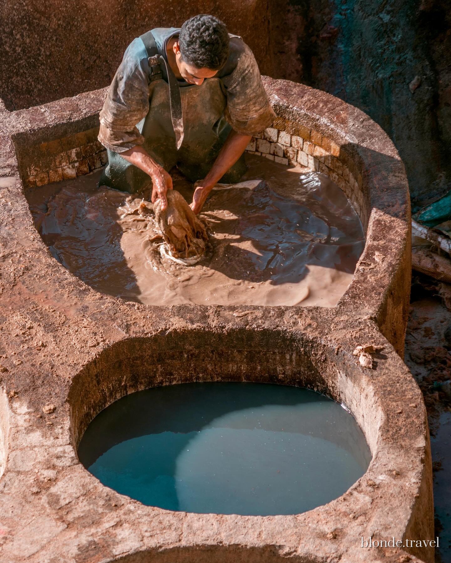 A tannery worker handles a hide by hand in a stone vat at Chouara.
