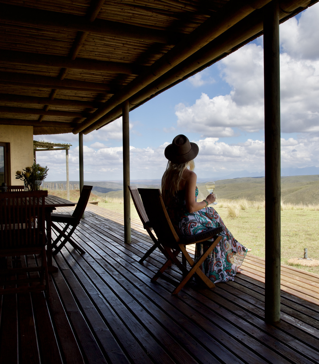 Olga sitting with a glass of wine on the veranda of a Gondwana villa at dusk
