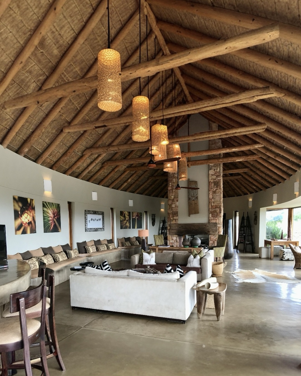 Large thatched living room with a stone fireplace and sofas in a Gondwana villa