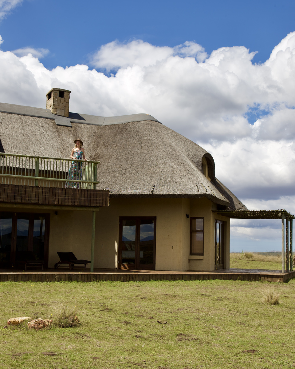 Olga standing on the upper balcony of a two-storey thatched villa at Gondwana Game Reserve