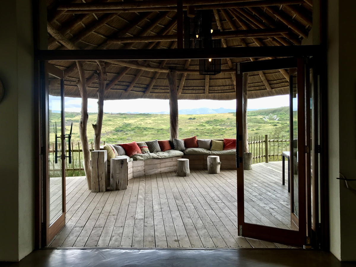 Open doors from a Gondwana villa framing a wooden veranda and green hills