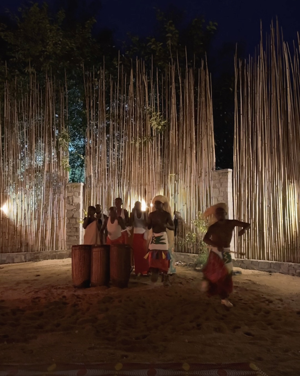 A performer in a raffia headdress dances in front of drummers at Gorilla Guardians Village.
