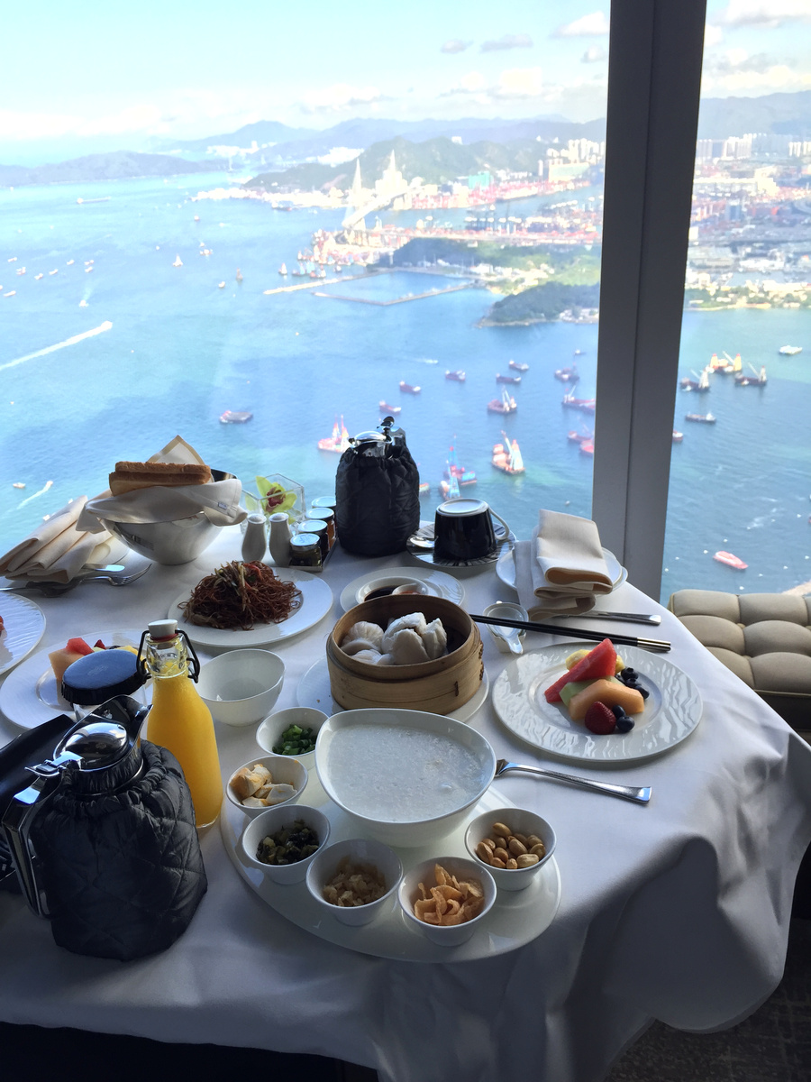 Room-service breakfast with congee, steamed buns, fried noodles and fruit above Victoria Harbour