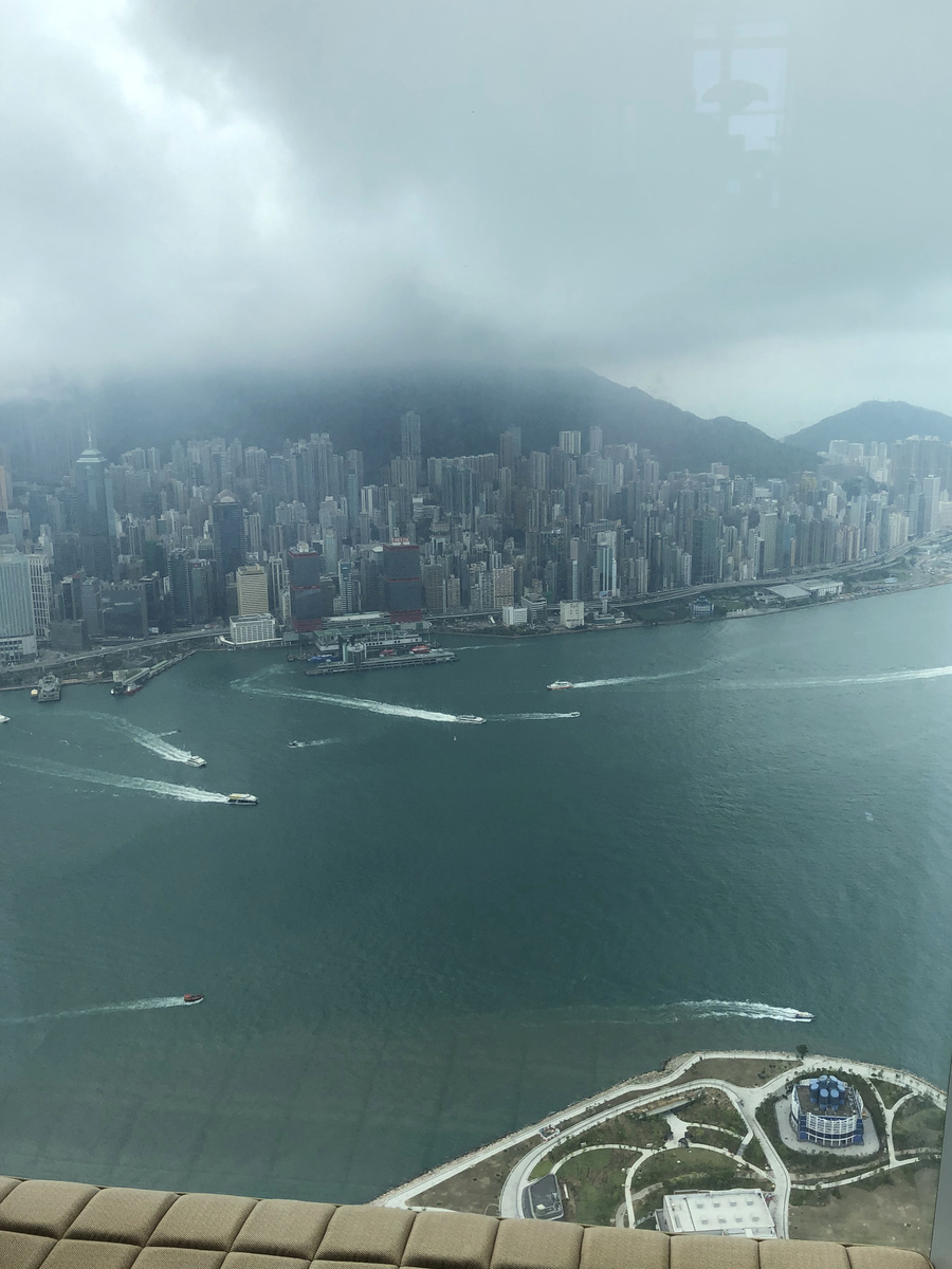 Mist over Hong Kong Island and boats crossing Victoria Harbour, seen from a high Ritz-Carlton window