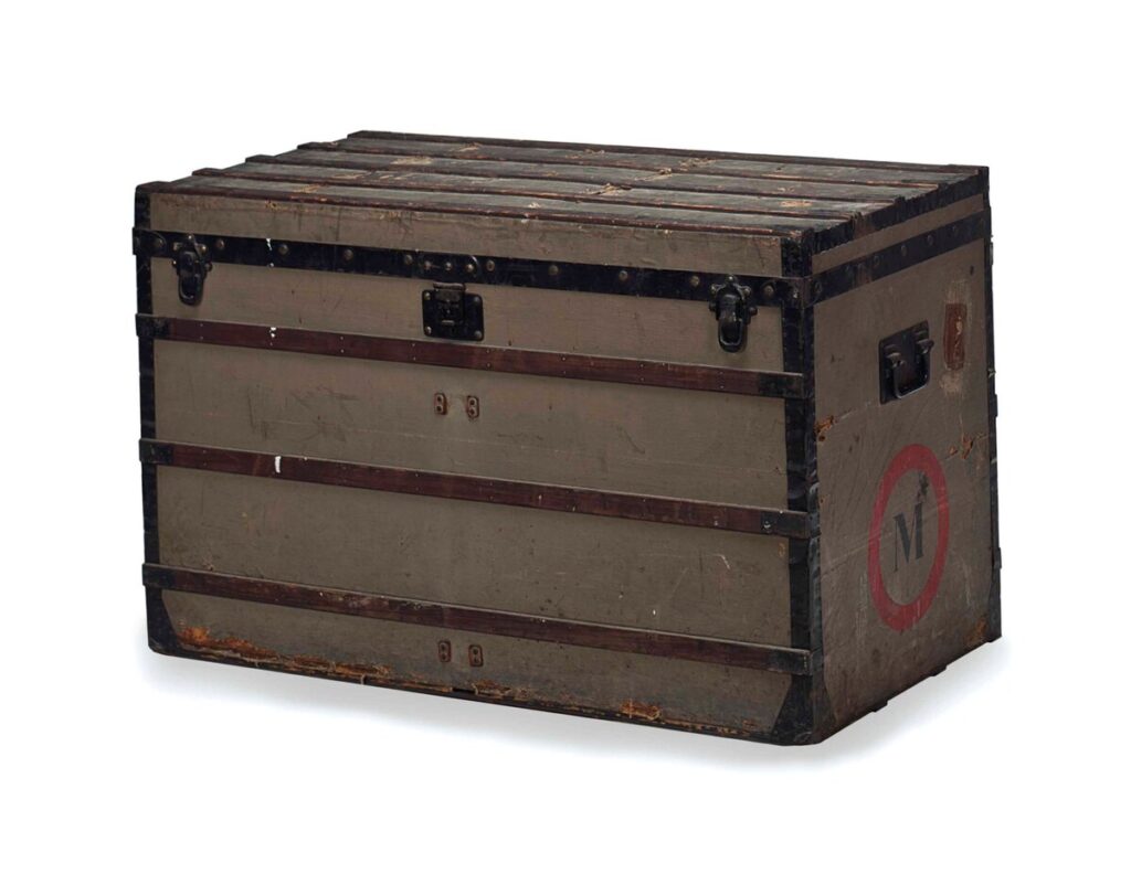 Early Louis Vuitton Trianon grey canvas trunk with a flat slatted lid, dark reinforcing bands and iron fittings.