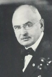 Small black-and-white portrait of Marcellus F. Berry, bald and moustached, wearing round spectacles, a dark suit and bow tie.