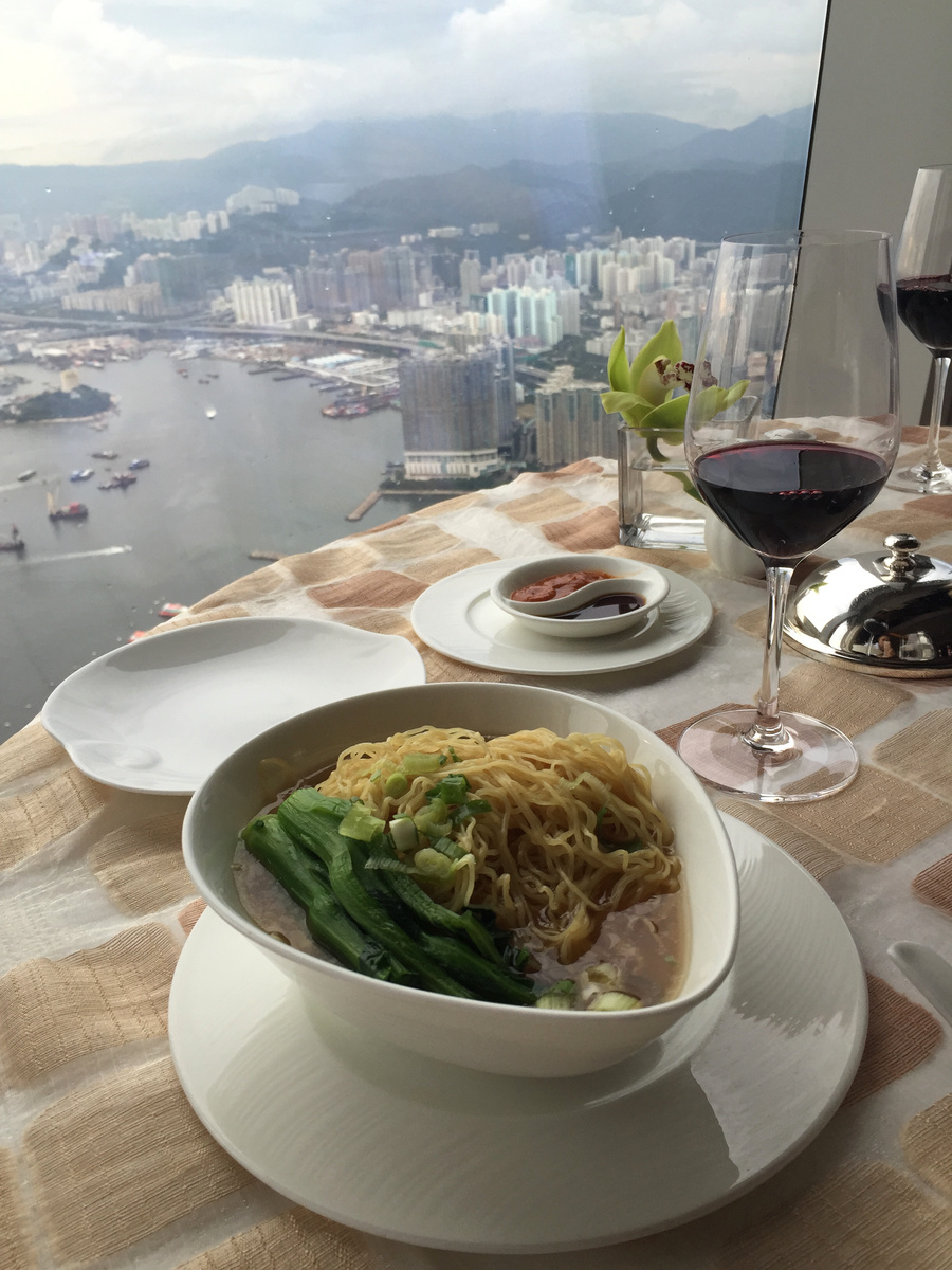 A bowl of noodles and red wine beside a harbour-view window at The Ritz-Carlton, Hong Kong