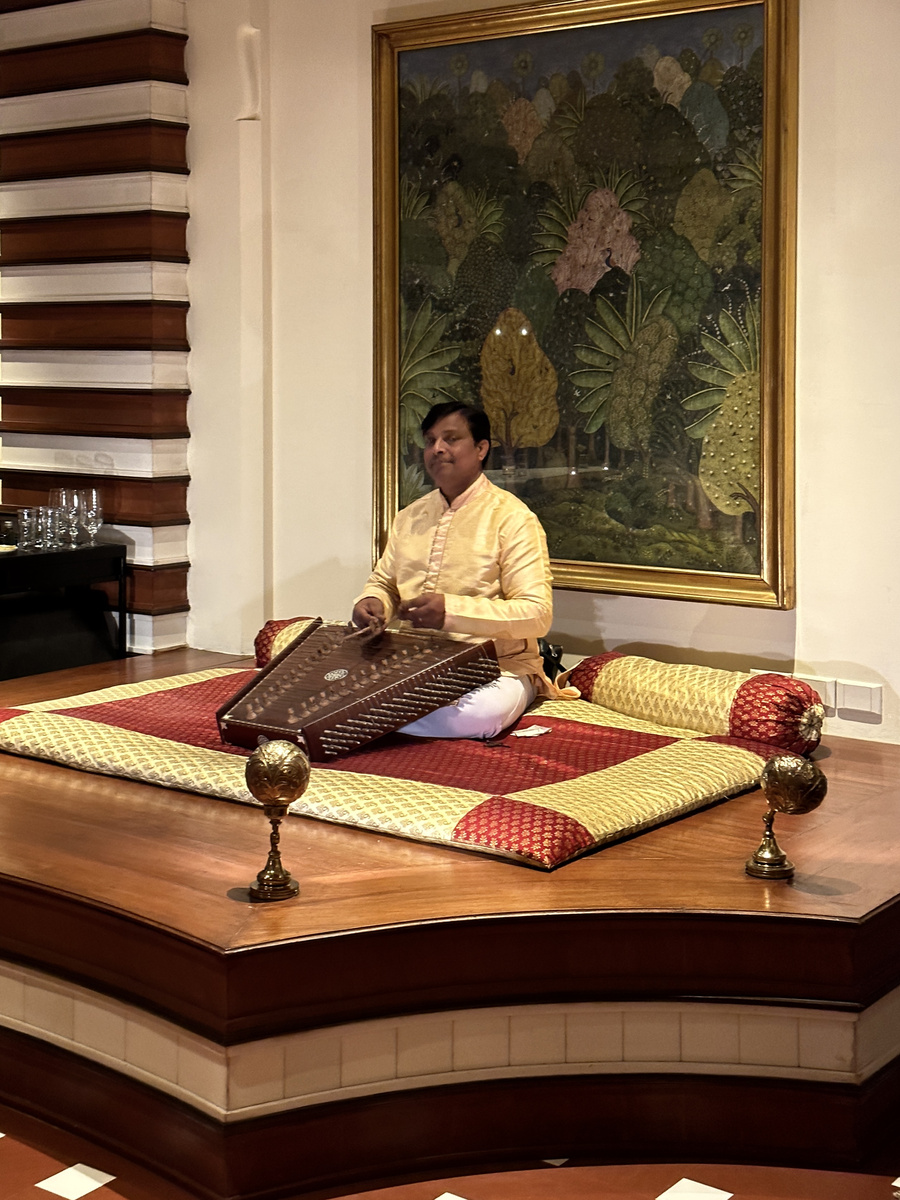 A musician plays a santoor on a raised platform during dinner at The Oberoi Amarvilas.