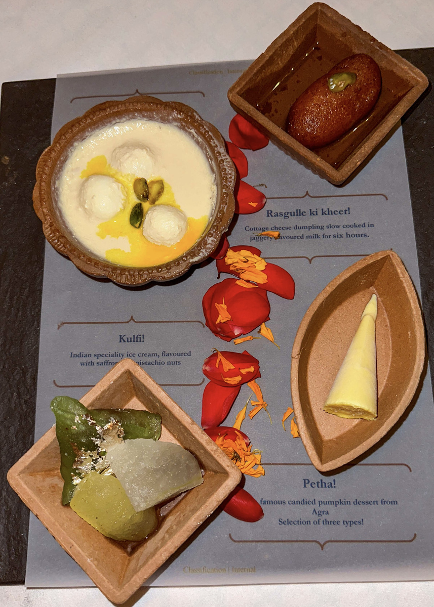 Four Indian desserts, including petha and kulfi, arranged on a printed tasting mat at The Oberoi Amarvilas.