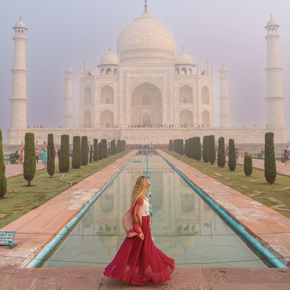 Olga in a red skirt beside the reflecting pool with the Taj Mahal behind her in Agra.