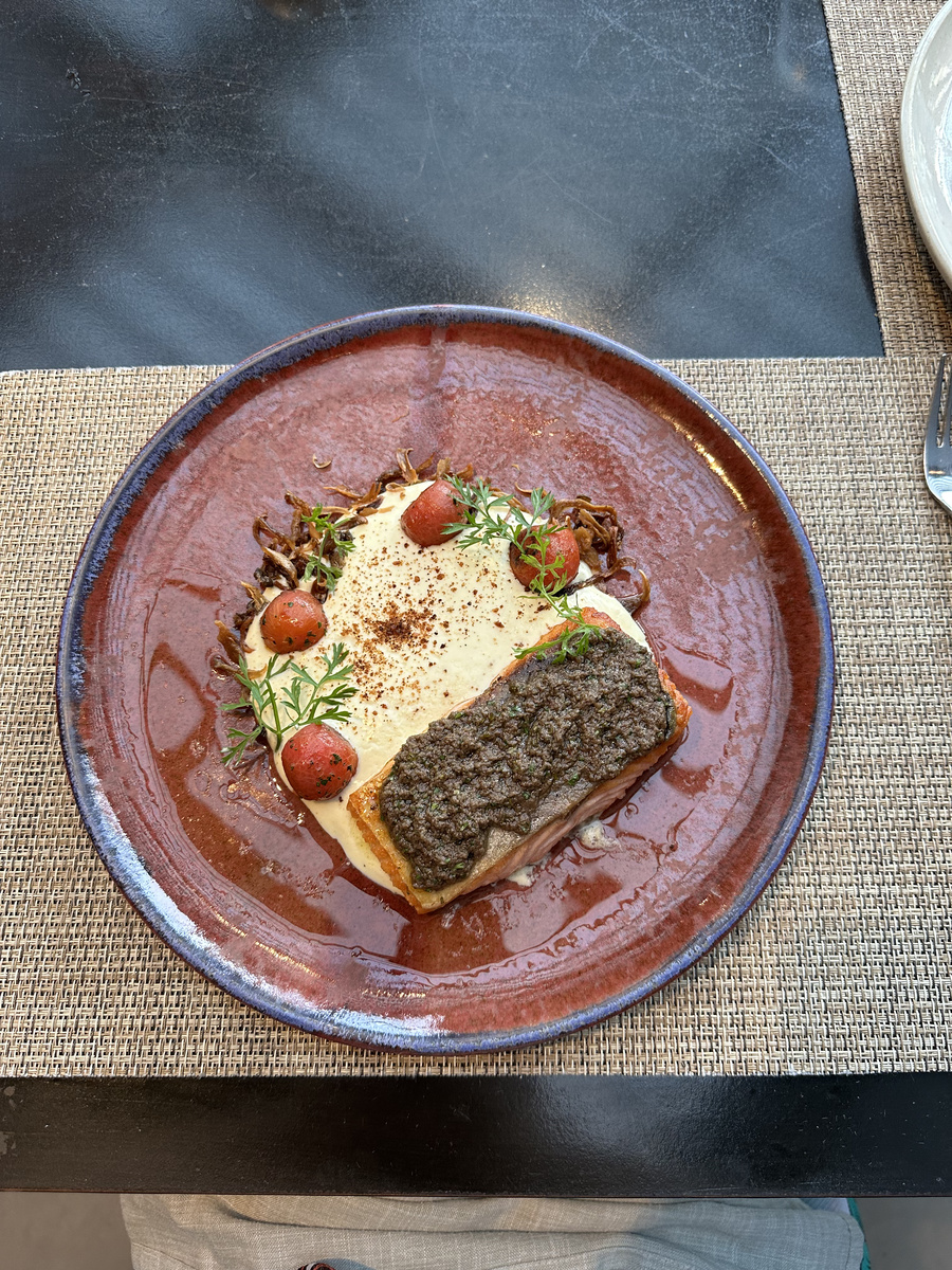 Crisp-skinned salmon is served with creamy chuchoca, small tomatoes and herbs at Estró in The Ritz-Carlton Santiago.