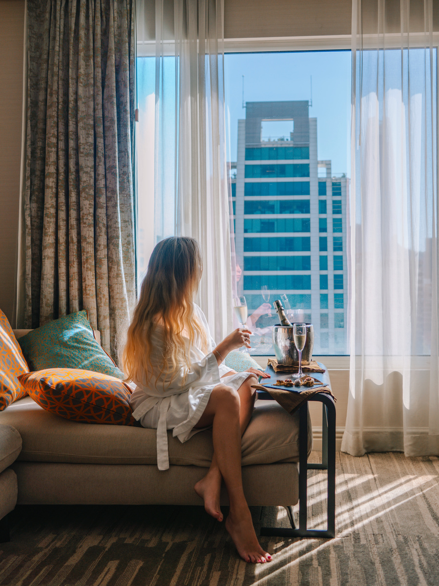 Olga sits on a sofa beside the window of a Ritz-Carlton Santiago guest room, with city towers beyond.