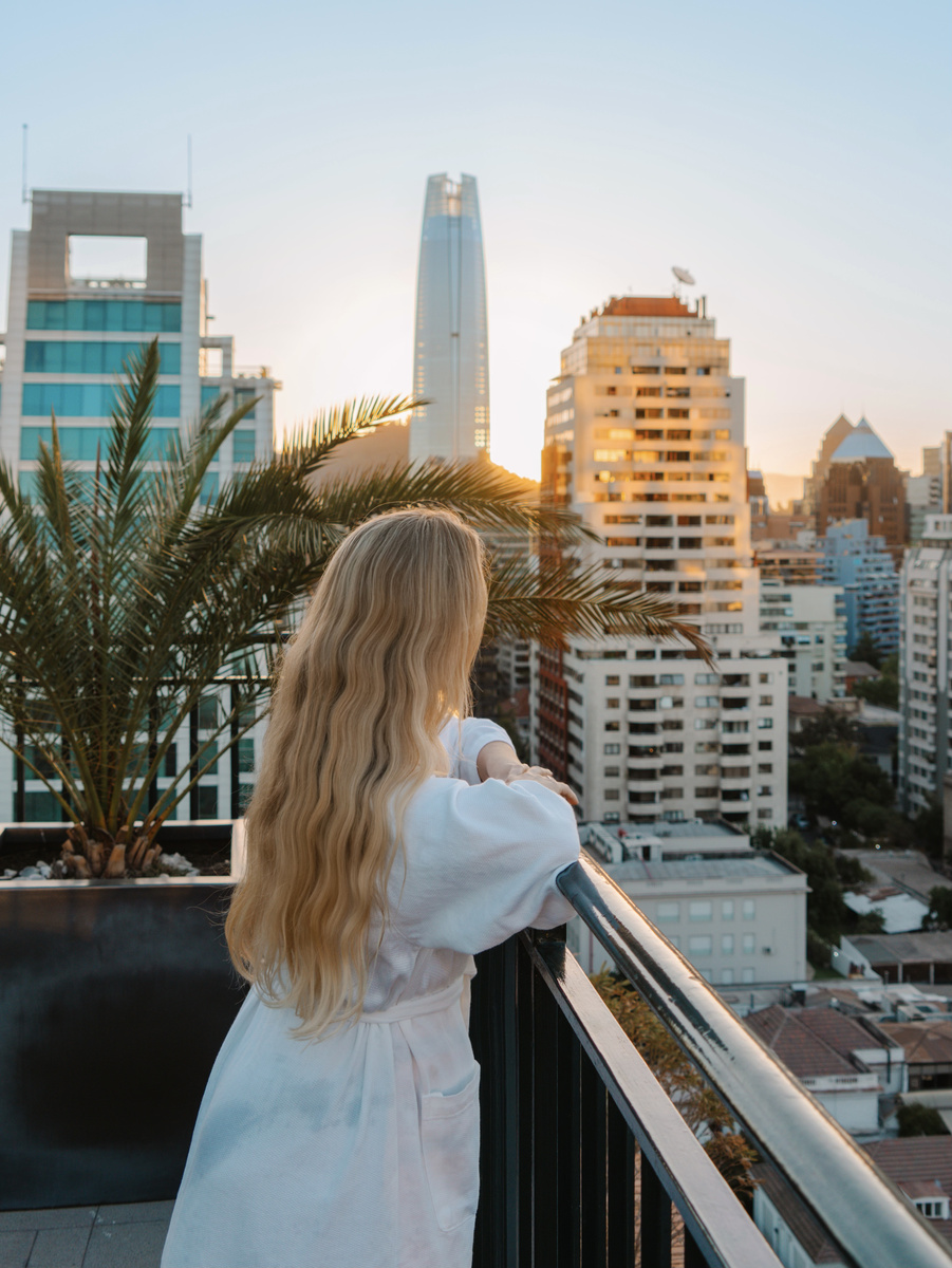 Olga looks across Santiago's skyline from the rooftop pool terrace at sunset.
