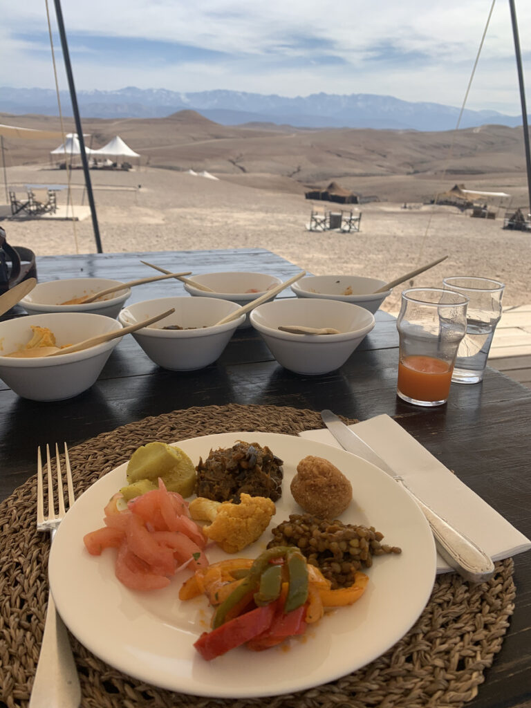 Moroccan breakfast on an outdoor table overlooking Scarabeo Camp and the Atlas Mountains