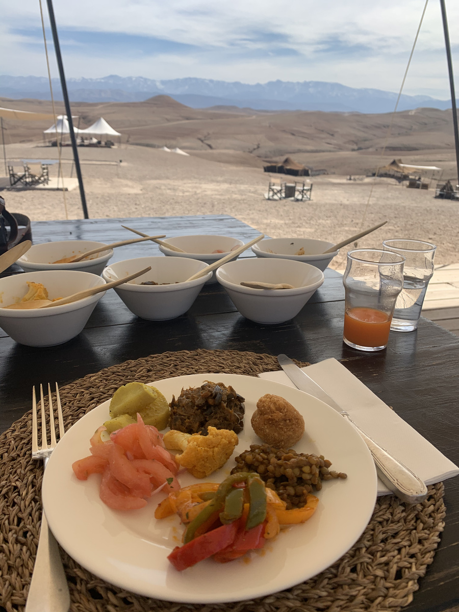 Moroccan breakfast on an outdoor table overlooking Scarabeo Camp and the Atlas Mountains