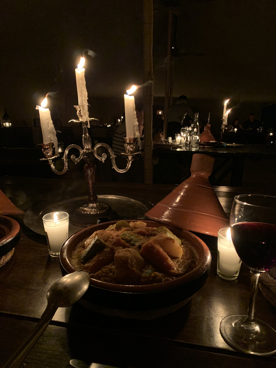 Vegetable tagine served beside candles and a candelabrum at Scarabeo Camp