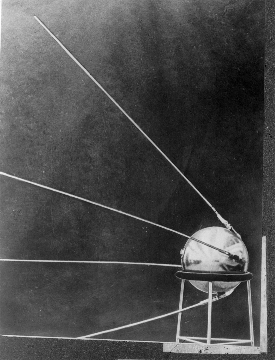 Sputnik 1, a polished metal sphere on a stand with four long radio antennae.