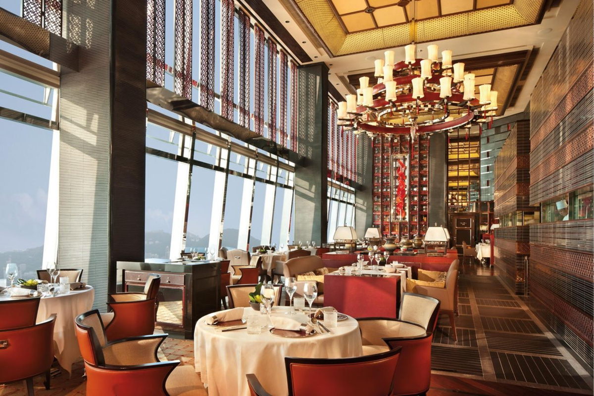 Tin Lung Heen dining room with red lacquered chairs, round tables and harbour-facing windows