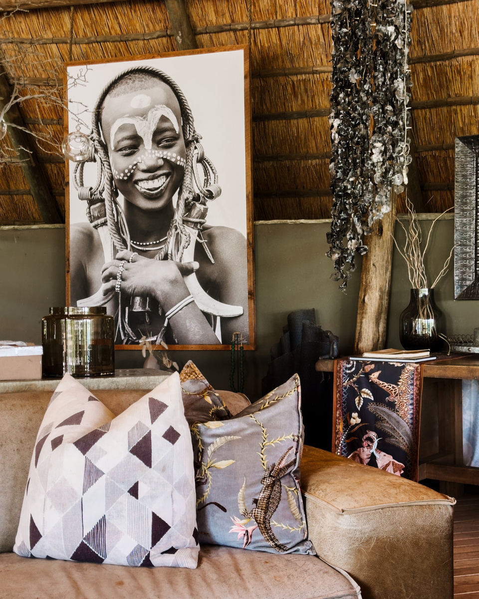 A black-and-white portrait, patterned cushions and woven details decorate the lounge at Victoria Falls River Lodge.
