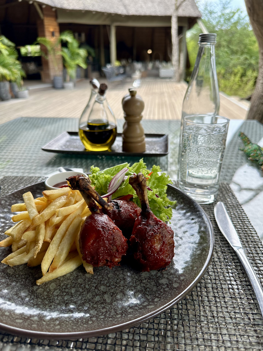 A glazed grilled course with fries and salad is served in the open restaurant at Victoria Falls River Lodge.