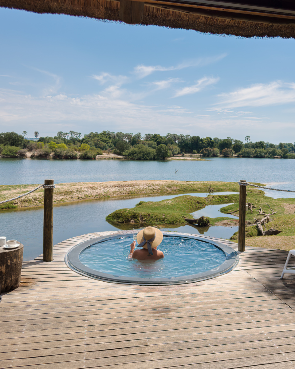 Olga sits in the private plunge pool of a Victoria Falls River Lodge tented suite, looking across the Zambezi River.