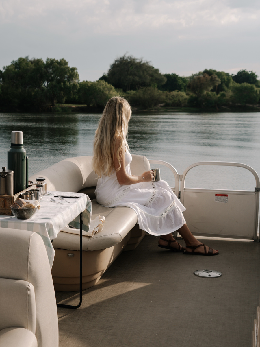 Olga sits at the bow of a small boat during a morning cruise on the Zambezi River.