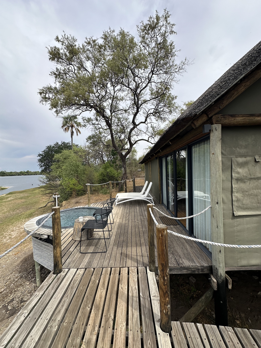 A canvas-and-thatch tented suite stands on a wooden deck beside the Zambezi River at Victoria Falls River Lodge.
