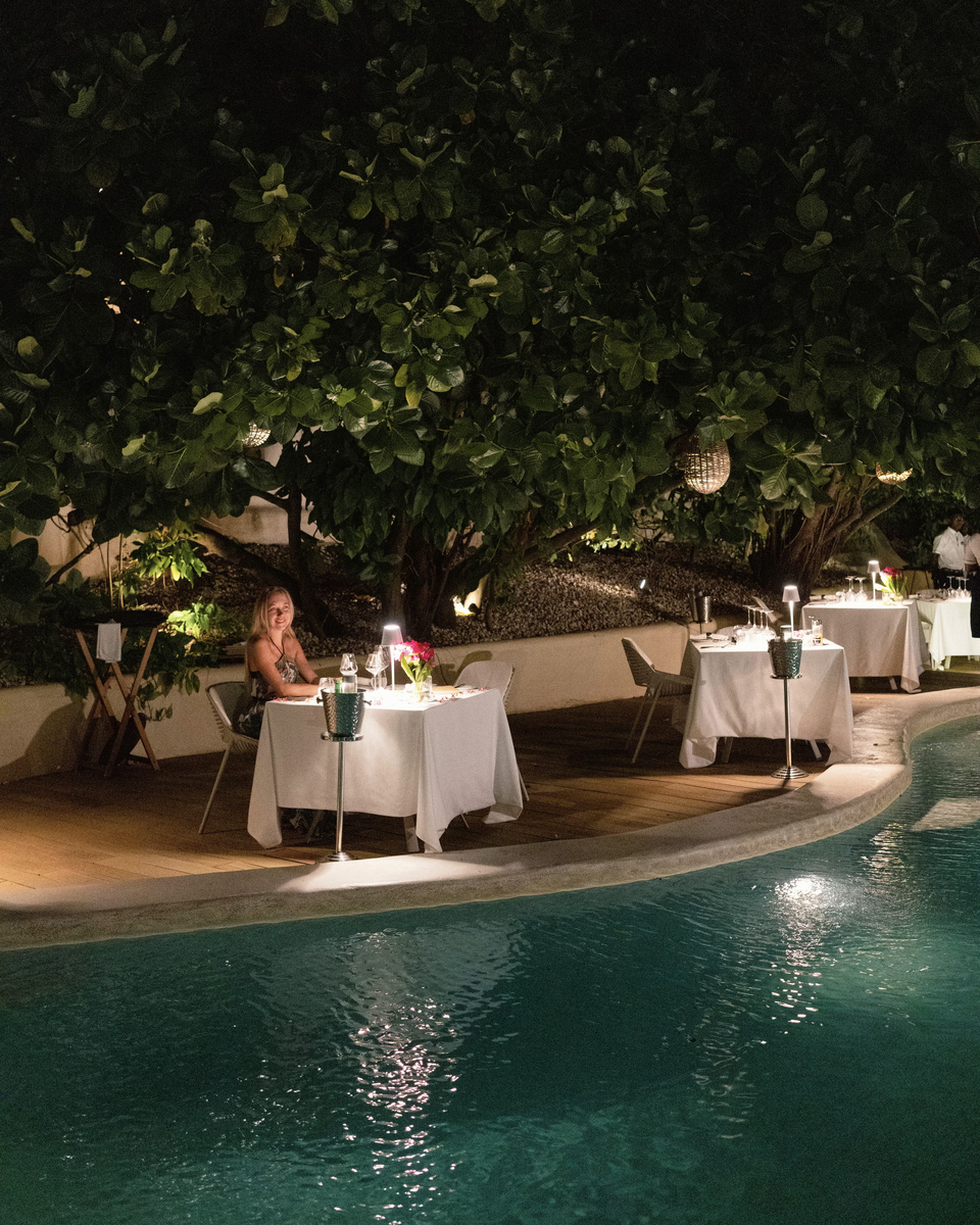 Dinner tables glow beneath a broad tree beside the swimming pool at Doors to Zanzibar.