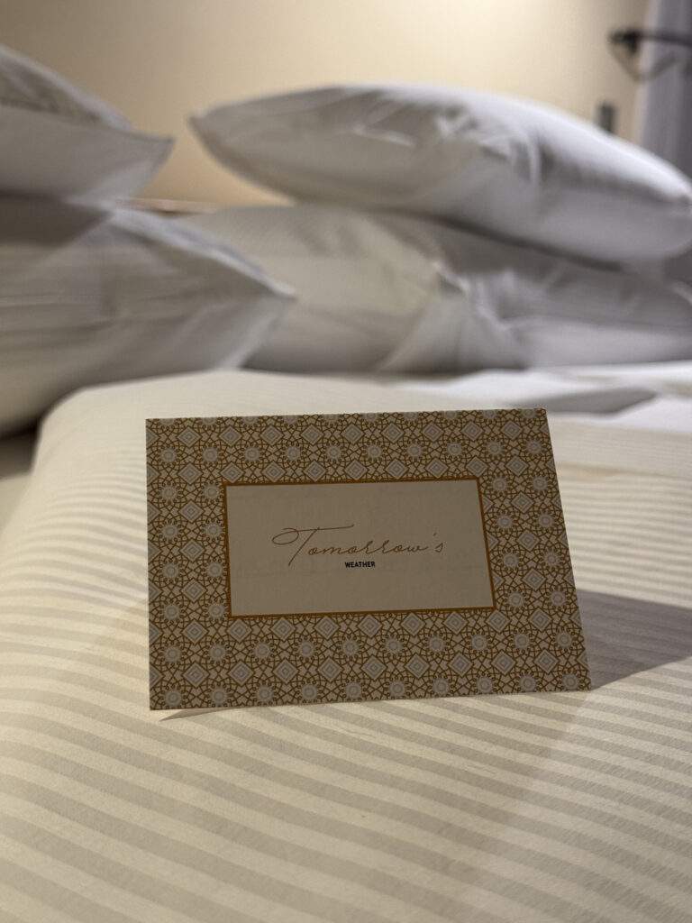 A patterned card on the bed promises tomorrow weather at Zanzibar White Sand.