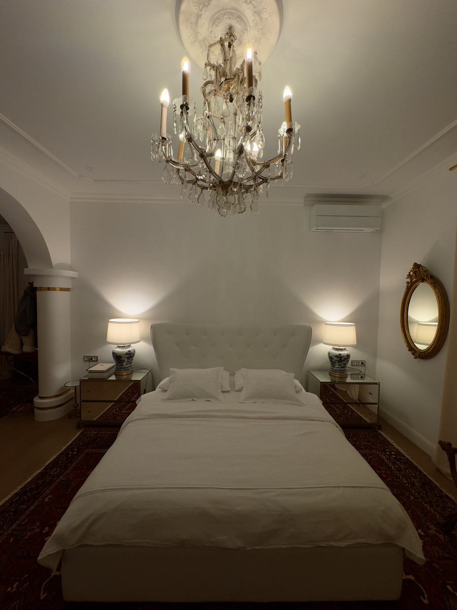 The bedroom at Villa Adora with a chandelier and paired bedside lamps.
