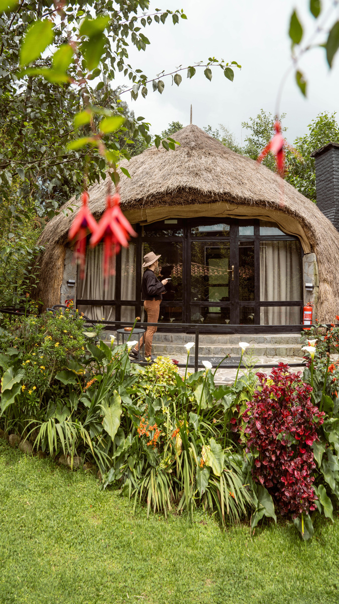 Olga standing among flowers outside a round thatched cottage at Amarembo in Rwanda.