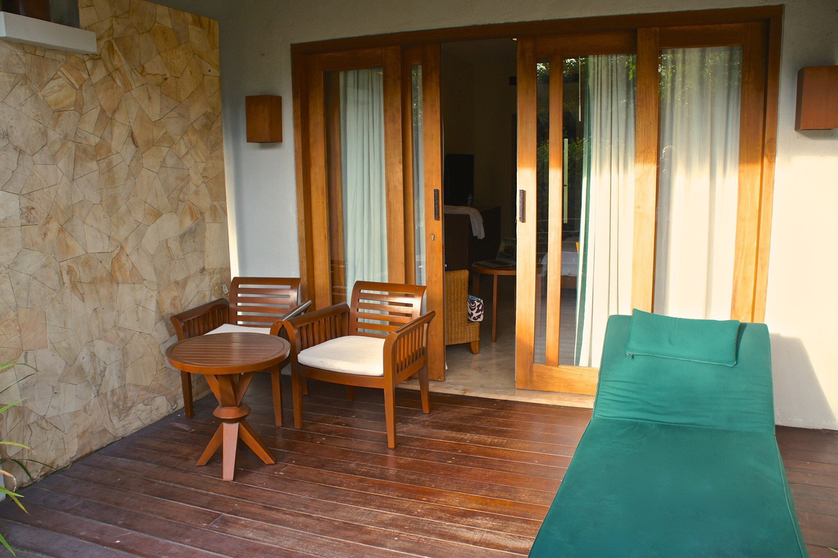 Wooden chairs and a green lounger on the terrace outside my Deluxe Suite.
