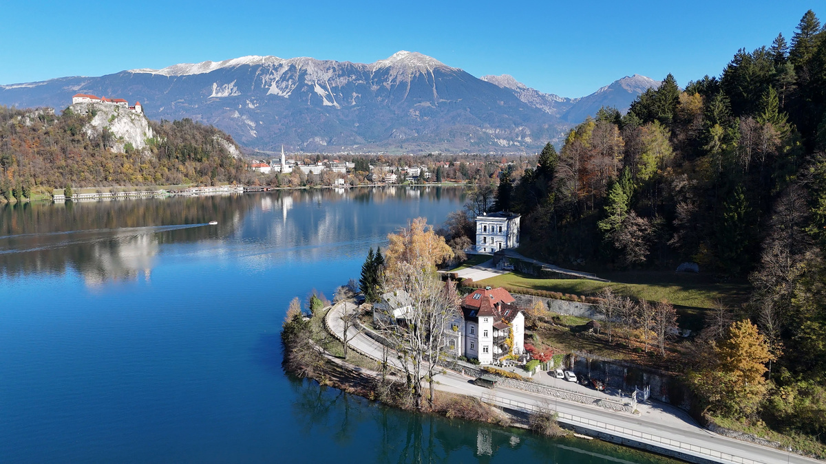 Aerial view of Adora Luxury Hotel beside Lake Bled, with Bled Castle and mountains beyond.