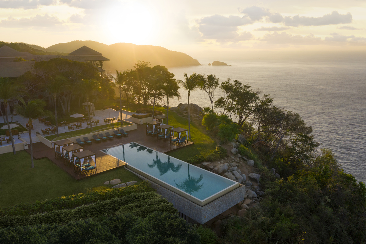 Aerial view of Reflections Pool at Banyan Tree Cabo Marqués on the rocky Pacific cliff at sunset.