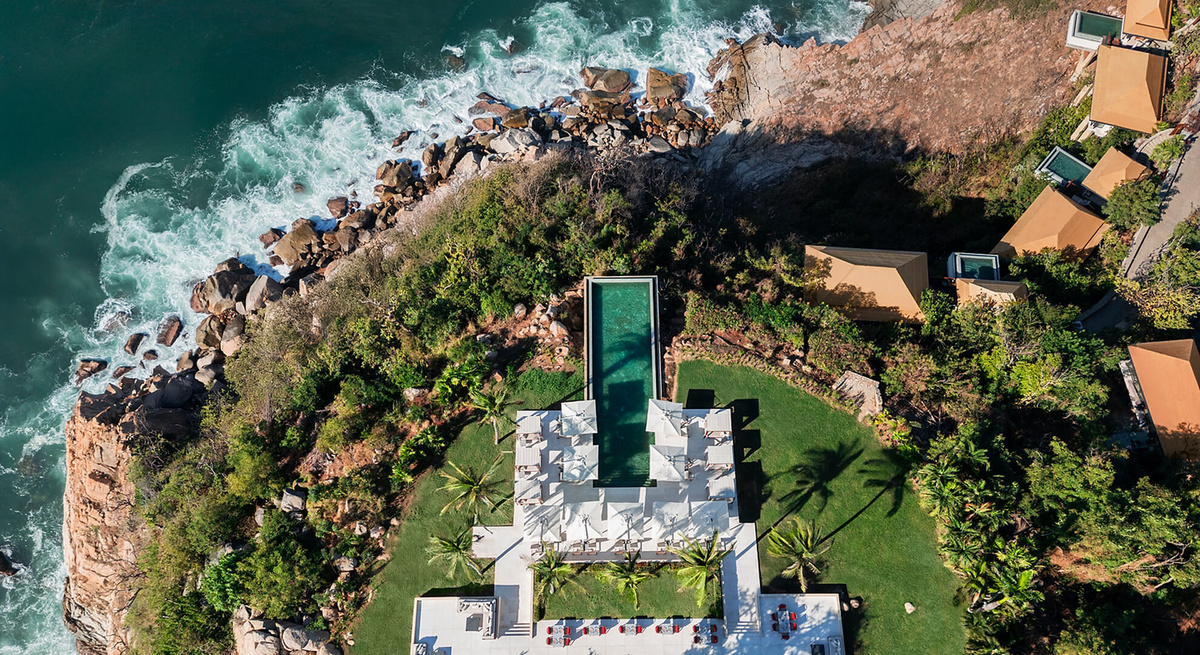 Top-down aerial view of Reflections Pool, cliffside villas and Pacific waves below Banyan Tree Cabo Marqués. Courtesy of Banyan Tree.