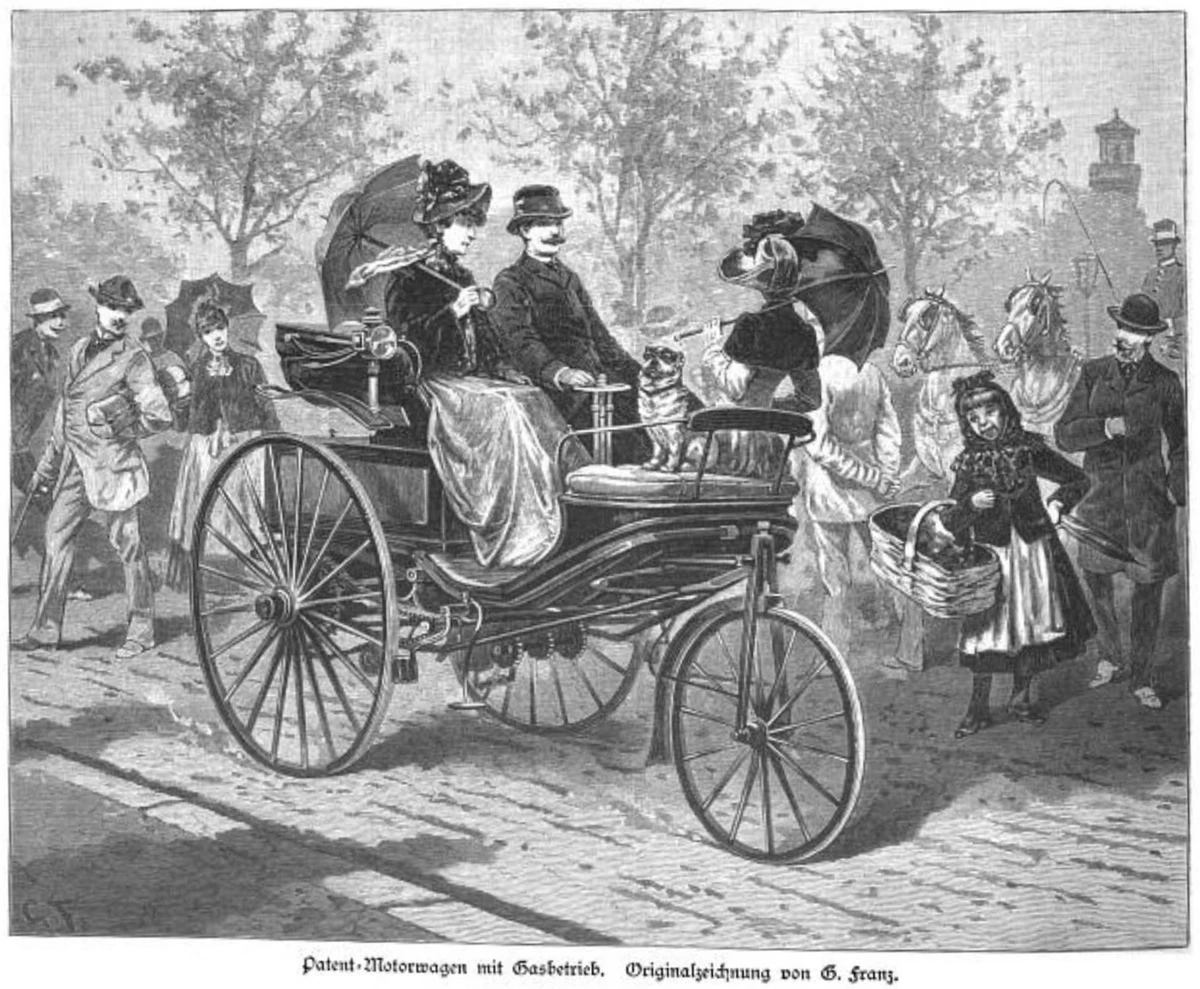 An 1888 engraving of a man and woman in a three-wheeled Benz among pedestrians and horse traffic.