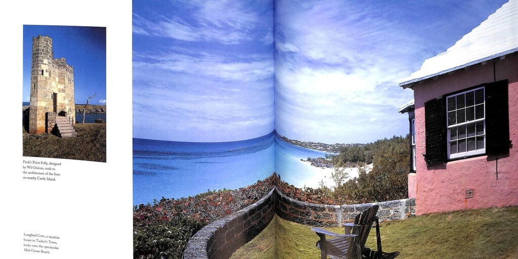 An open spread with a pink cottage and chairs on a lawn above a turquoise bay and white beach, beside a stone folly tower.